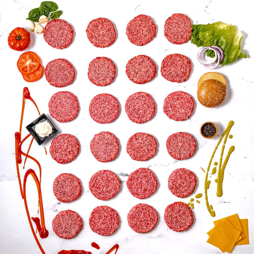 The Burger Box features 30 raw wagyu burger patties artfully arranged on a white surface, surrounded by classic burger toppings—cheese, lettuce, tomato, onion, condiments, and a bun—all delicious and delivered right to your door for the ultimate convenience.
