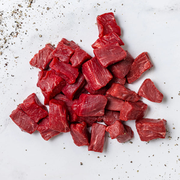 Sirloin Steak Tips cut into cubes arranged on a white surface, with black pepper sprinkled around.