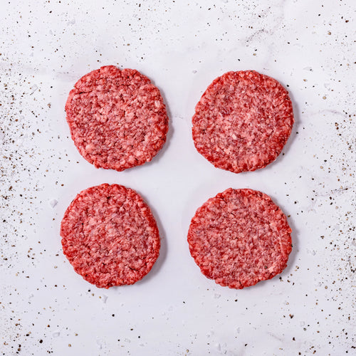 Four FREE American Wagyu + Angus burger patties arranged in a square on a white surface, with pepper and seasoning sprinkled around them.